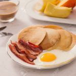 Breakfast plate with pancakes, eggs, bacon and fruit.